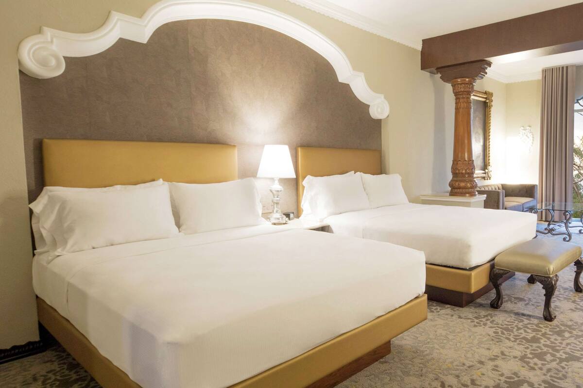 Een hotelkamer met twee bedden, een grote spiegel en uitzicht op de omgeving.