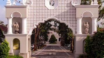 A grand entrance with intricate white carvings and statues on either side, leading to a pathway.