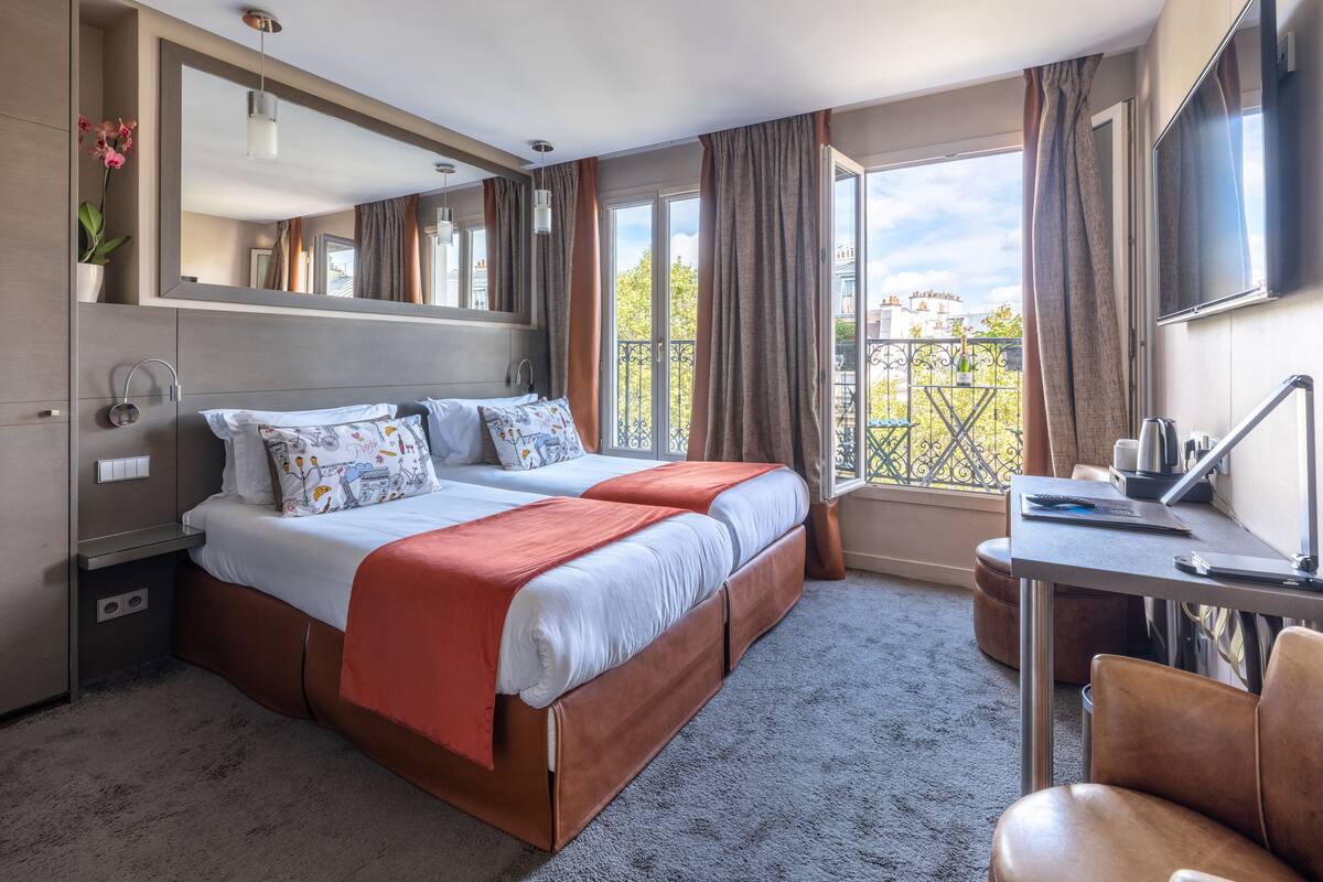 A hotel room with a bed, a desk, a chair, a TV, and a balcony with a view.