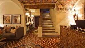 Una sala acogedora con un sofá, techo estampado y una escalera que lleva a otra habitación.