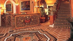 Un vestíbulo ornamentado con una escalera imponente, detalles de madera elaborados y baldosas con diseños.