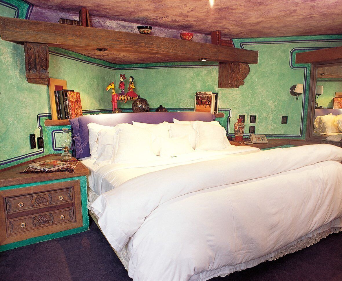 Un dormitorio con una cama grande, una mesita de noche con lámpara y un aparador.