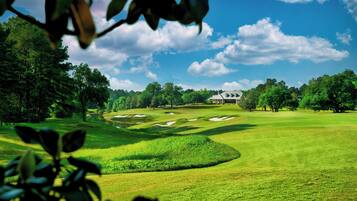 A golf course with a clubhouse and trees in the background.