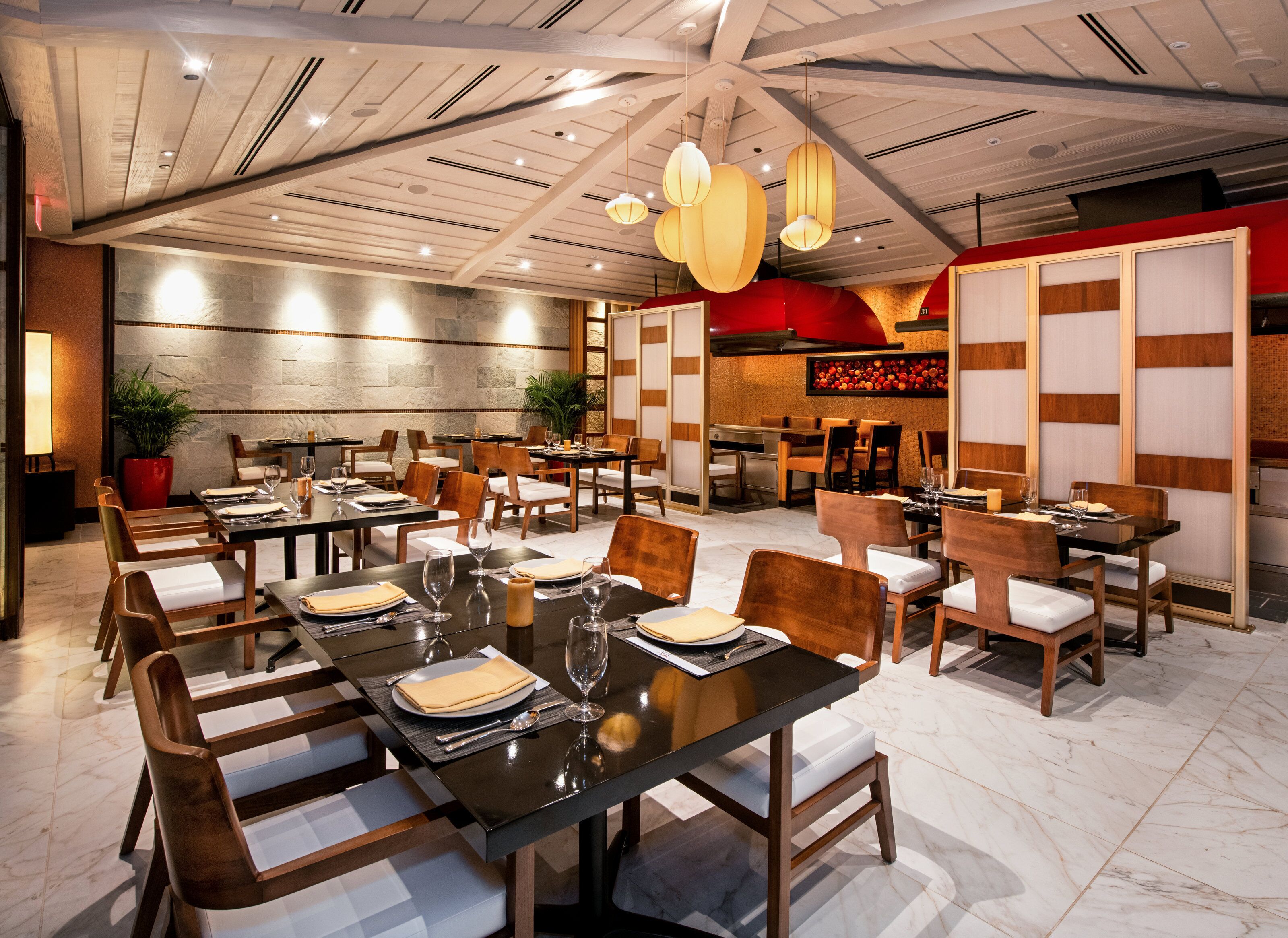 A restaurant with multiple dining tables, chairs, and a modern ceiling design.