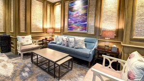 A well-furnished living room with a sofa, armchairs, a coffee table, and a large abstract painting on the wall. - Beau Rivage (Biloxi)