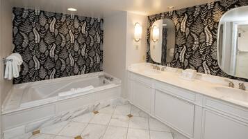 A bathroom with a large bathtub, two sinks, and a mirror.
