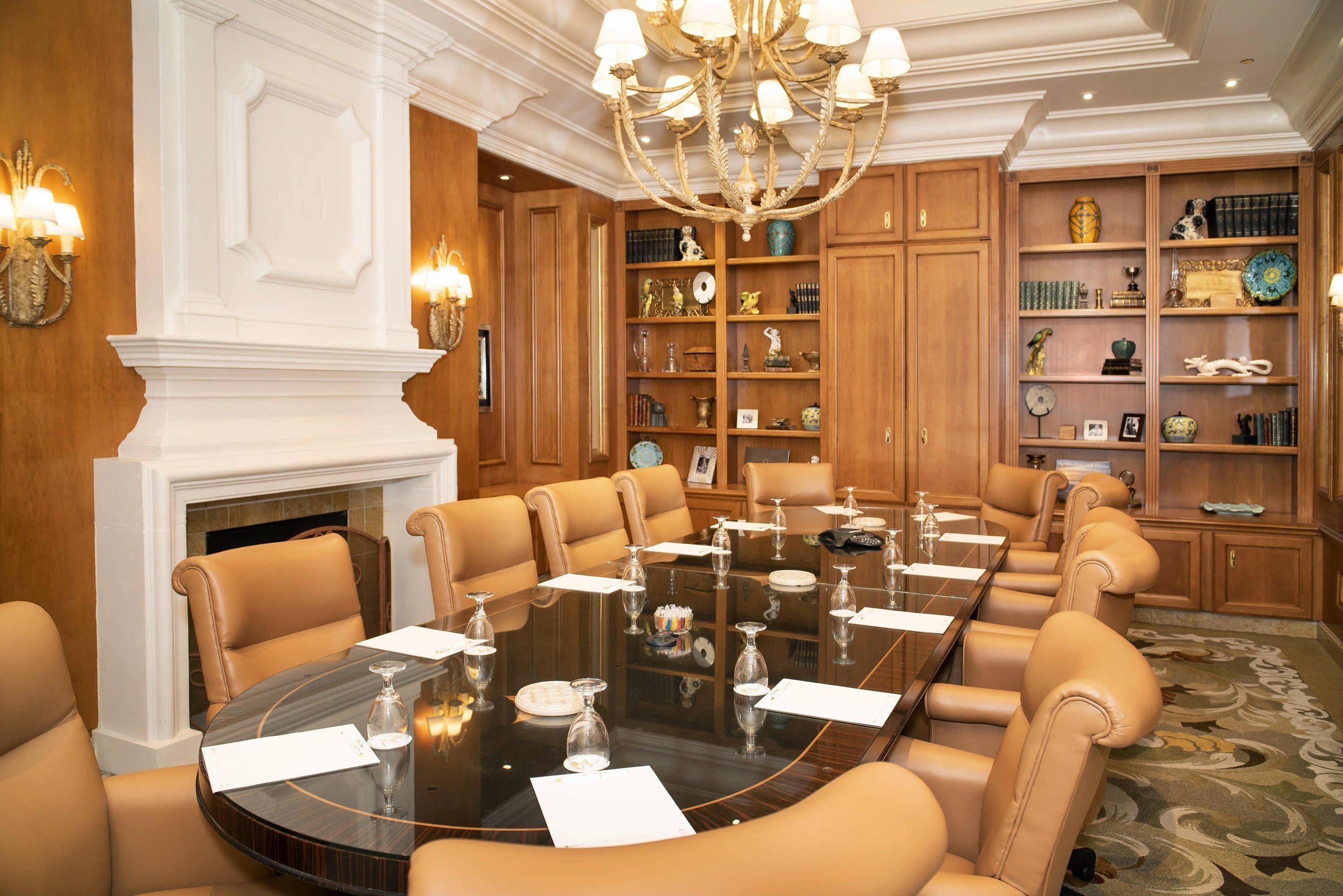 Une salle de réunion formelle, dotée d’une grande table ovale, de fauteuils en cuir, d’un lustre et de boiseries.