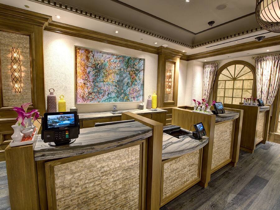 A hotel reception area with marble counters, a large abstract painting, and a view through arched windows.