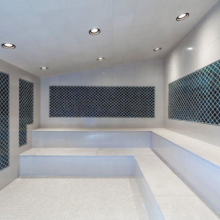 A modern bathroom with a geometric tile design, recessed lighting, and a central staircase.