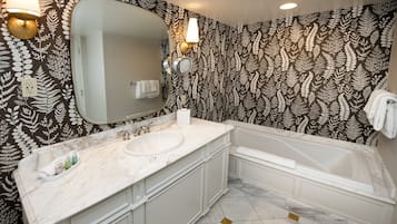 Casa de banho com um espelho grande, lavatório de mármore branco e banheira.