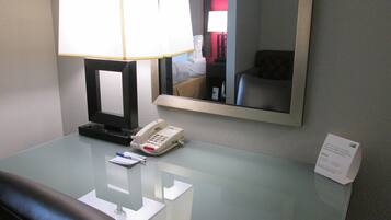 Habitación de hotel con escritorio, teléfono, lámpara, espejo y señal que indica acceso a internet de alta velocidad.