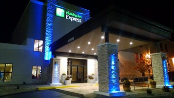 Un hotel Holiday Inn Express con fachada moderna, señalización iluminada y una entrada acogedora.