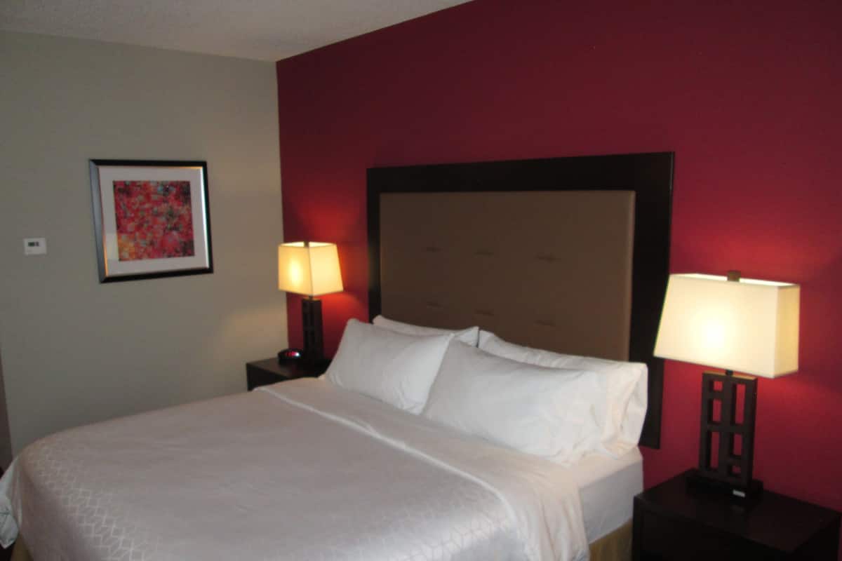 A neatly made bed with white linens, two bedside tables with lamps, and a framed picture on the wall.