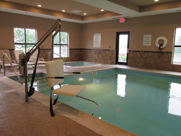 An indoor swimming pool with a lifeguard chair, a hot tub, and a sign warning no lifeguard on duty.