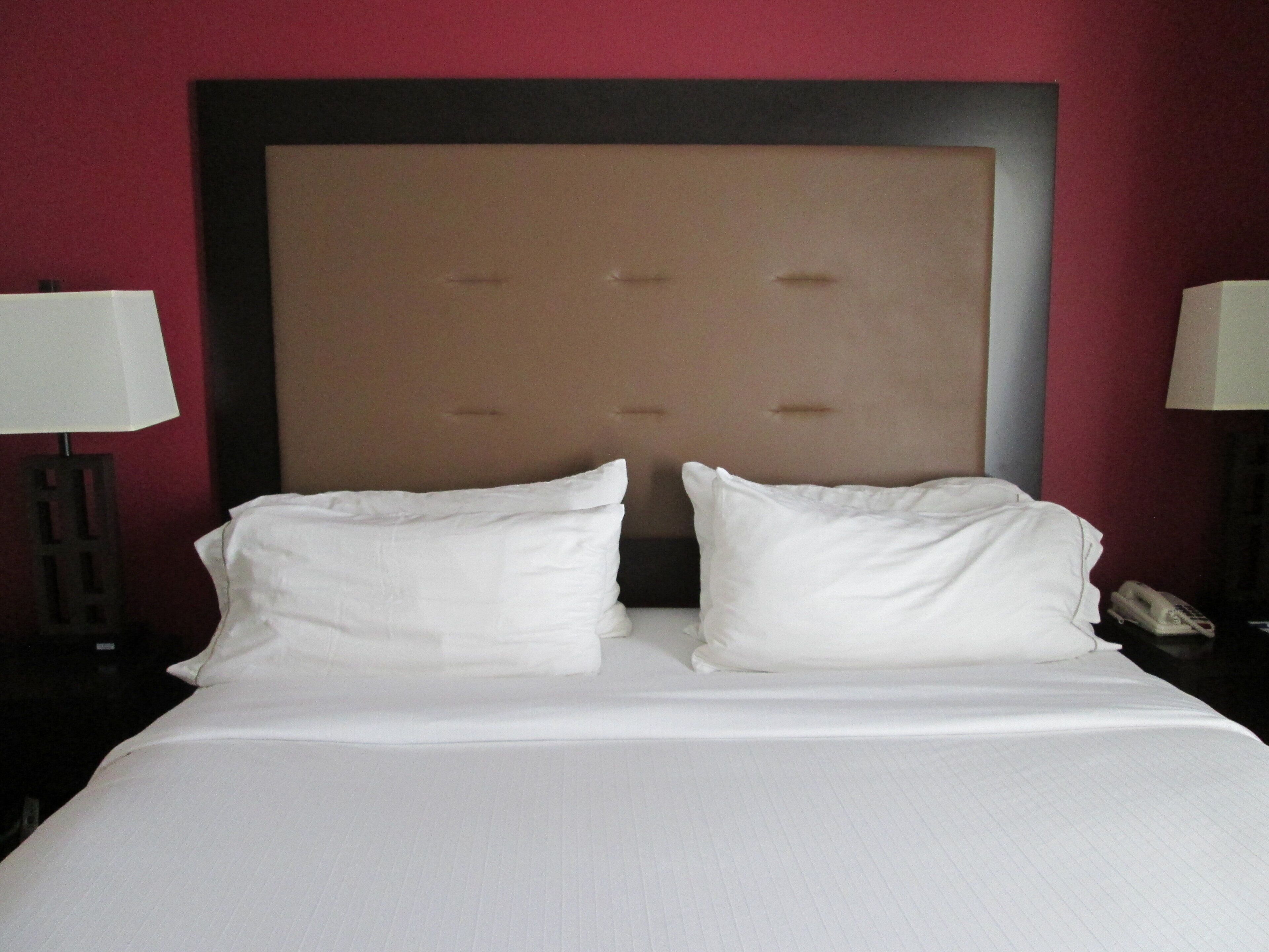 A hotel room with a large bed, two bedside lamps, and a telephone on the nightstand.