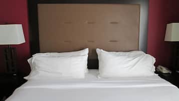 A hotel room with a large bed, two bedside lamps, and a telephone on the nightstand.