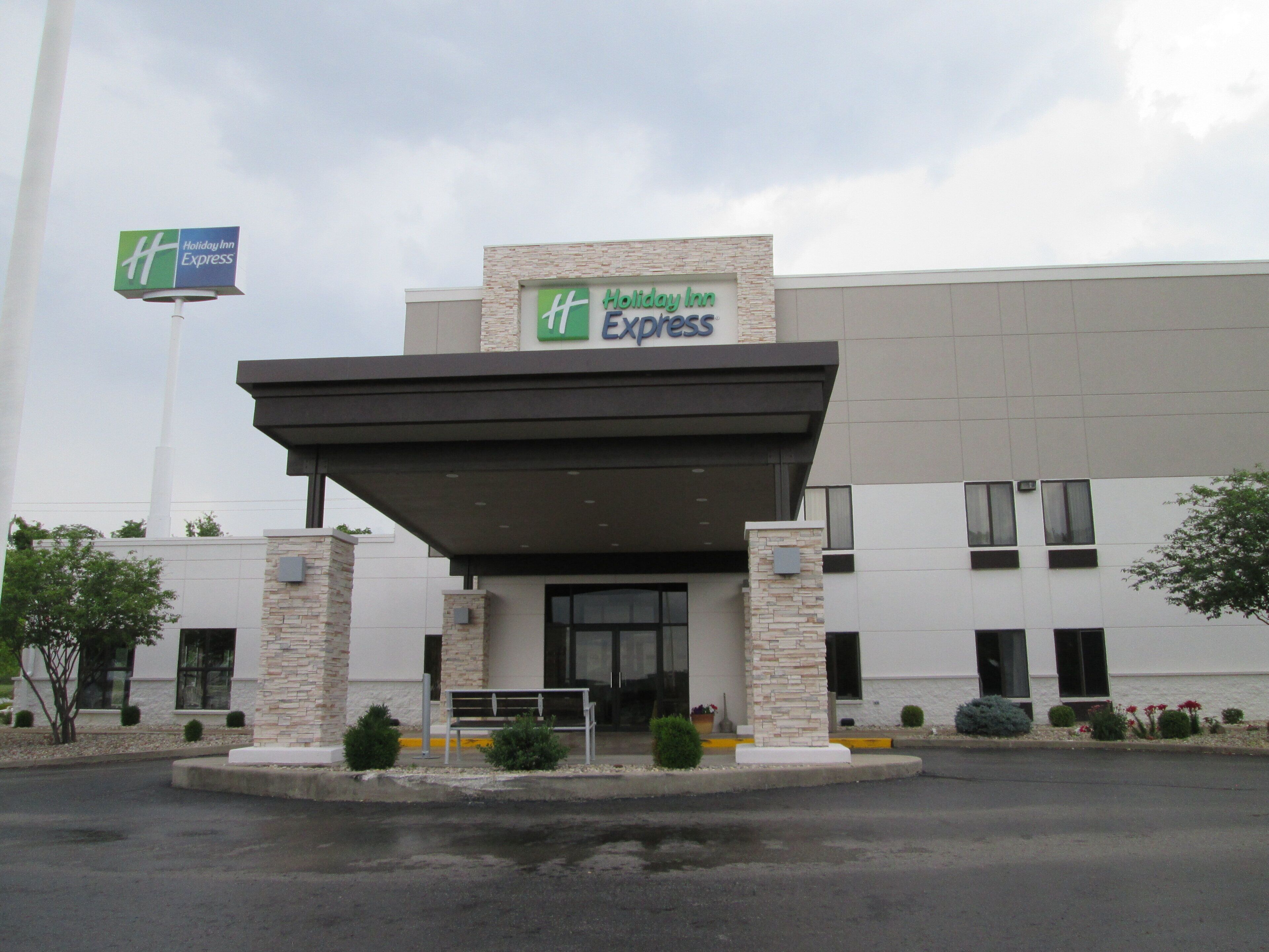 A Holiday Inn Express hotel with a covered entrance, stone pillars, and a clear sky.