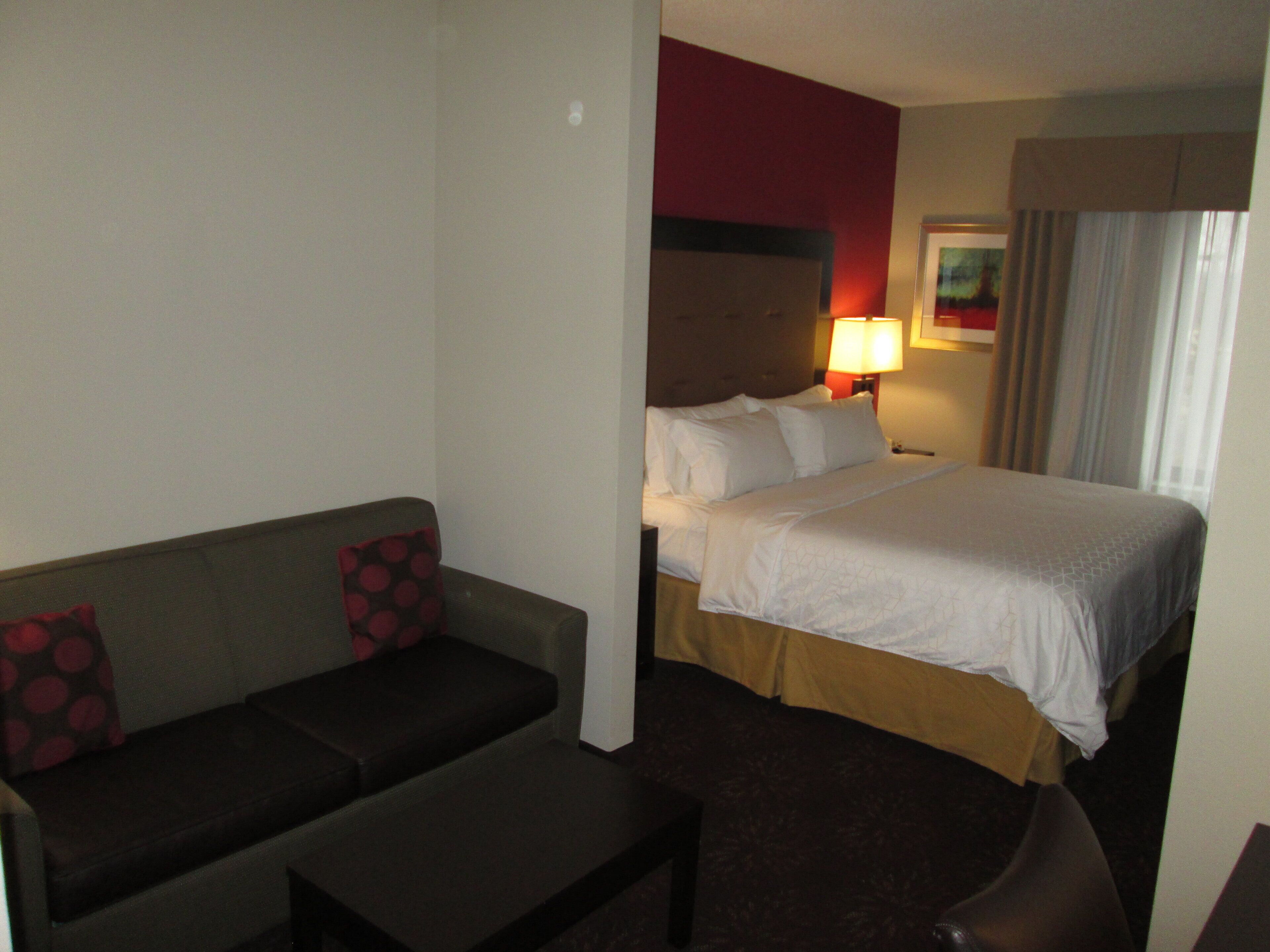 A hotel room with a bed, a sofa, and a small table.