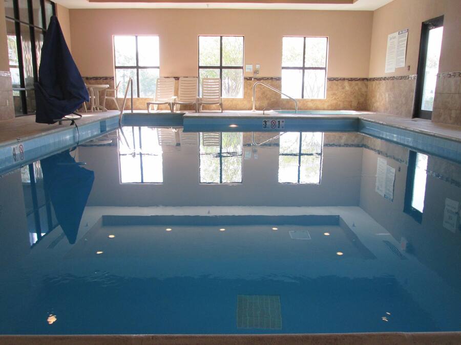 Ein hallenbad mit klarem Wasser, einem Rettungsschwimmerstuhl und einem Handtuchhalter.