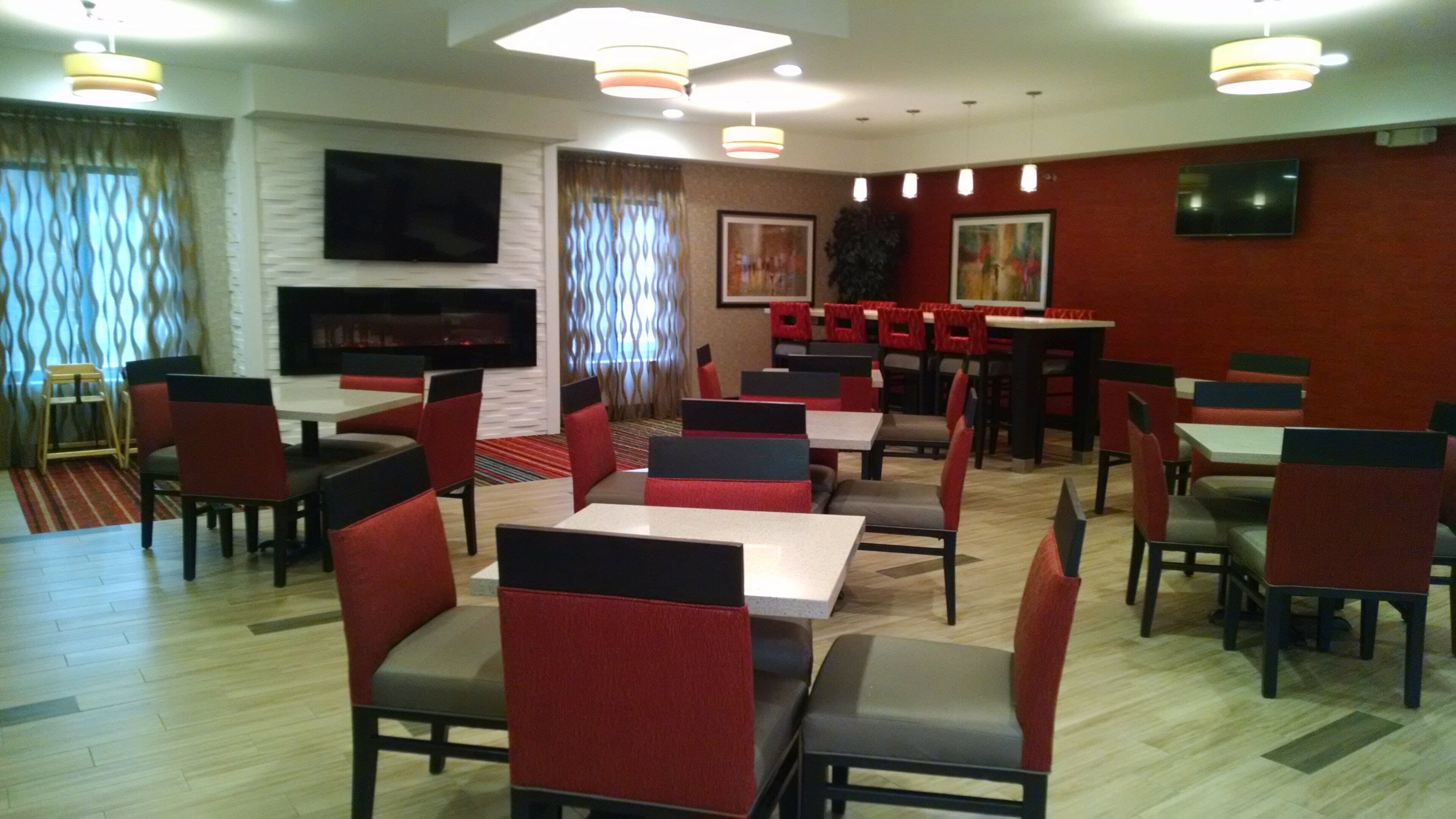 A restaurant with multiple tables and chairs, a flat-screen TV mounted on the wall, and a fireplace.