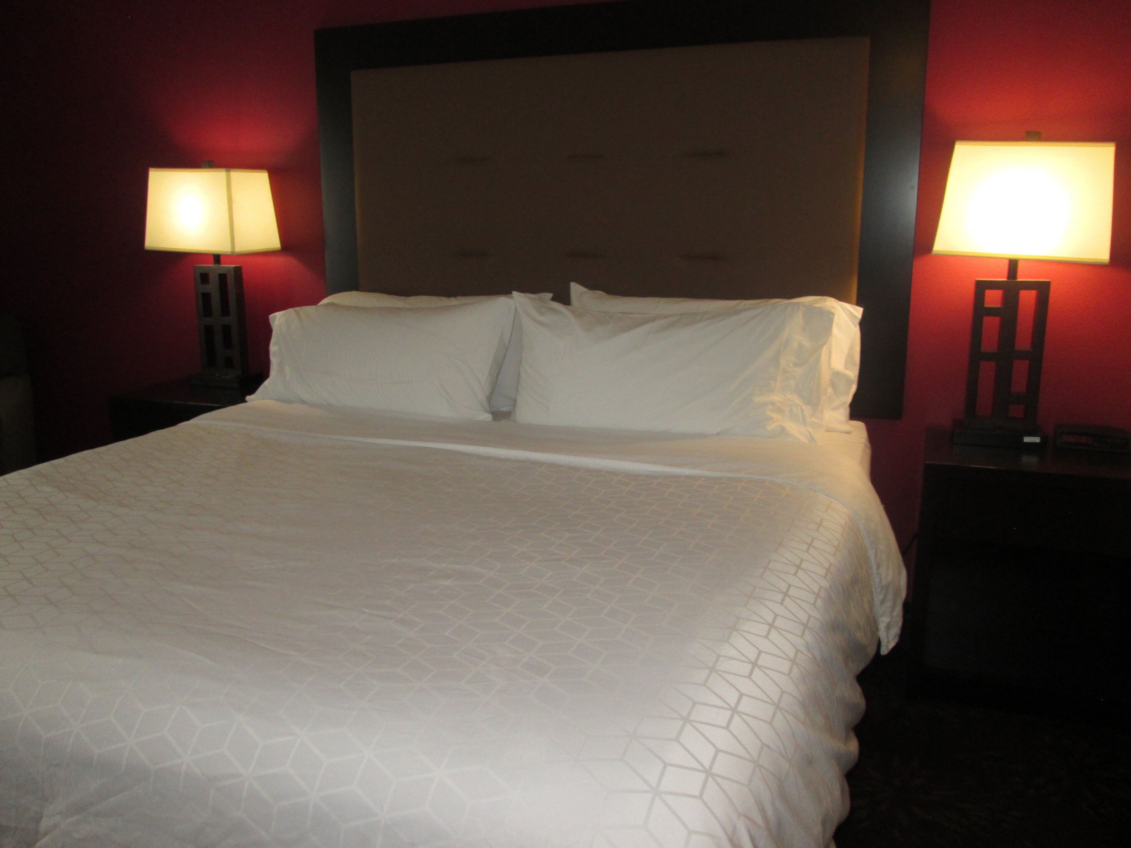 A hotel room with a large bed, two bedside tables with lamps, and a headboard.