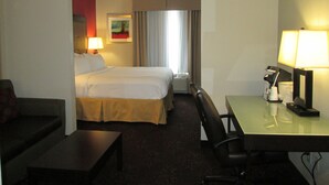 Une chambre d’hôtel avec un lit, un bureau, une chaise, une lampe et un tableau au mur.