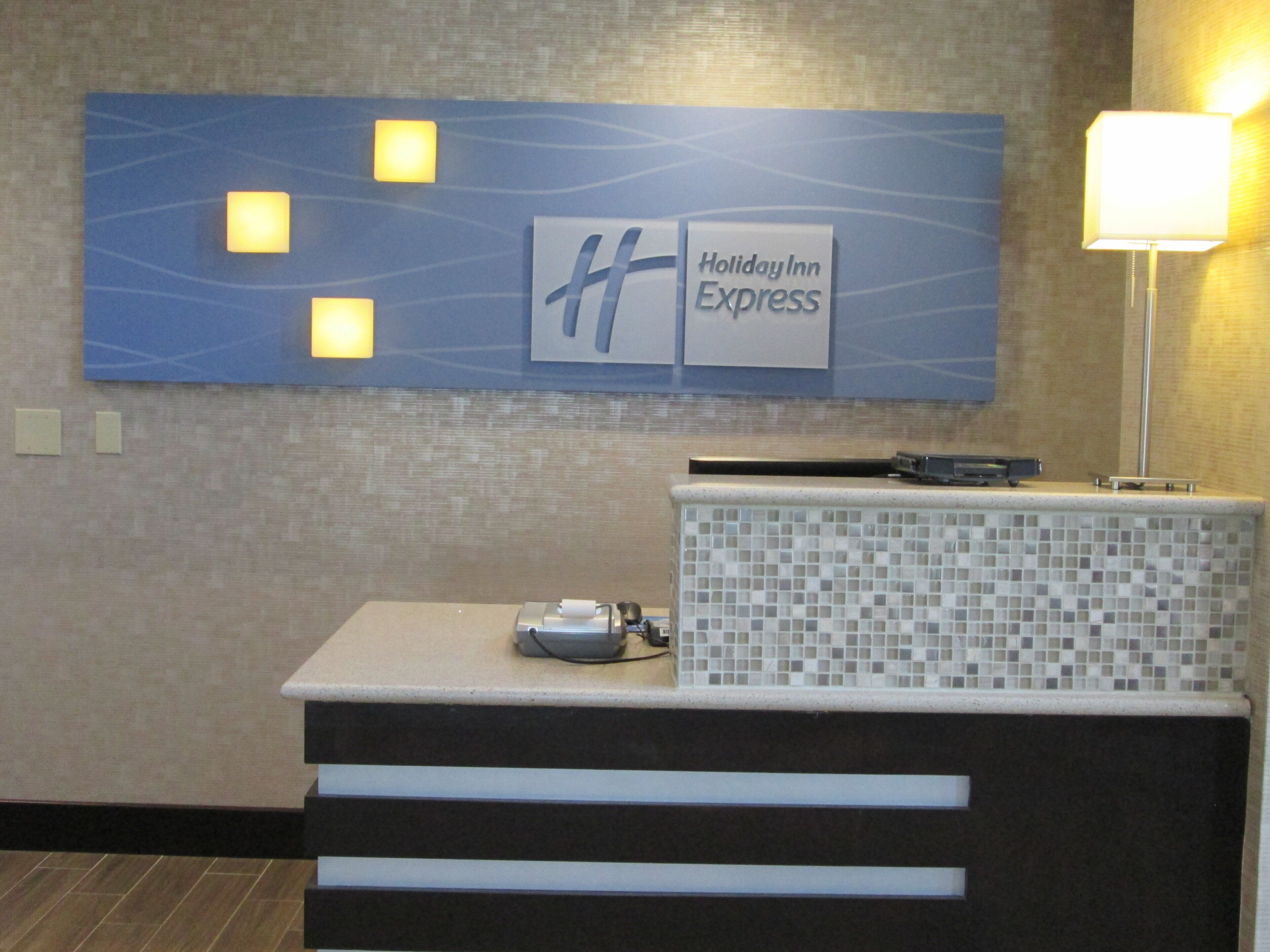 Una recepción con el letrero de Holiday Inn Express, un muro de azulejos y una lámpara.