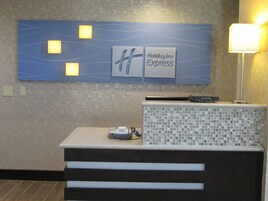 Una recepción con el letrero de Holiday Inn Express, un muro de azulejos y una lámpara.