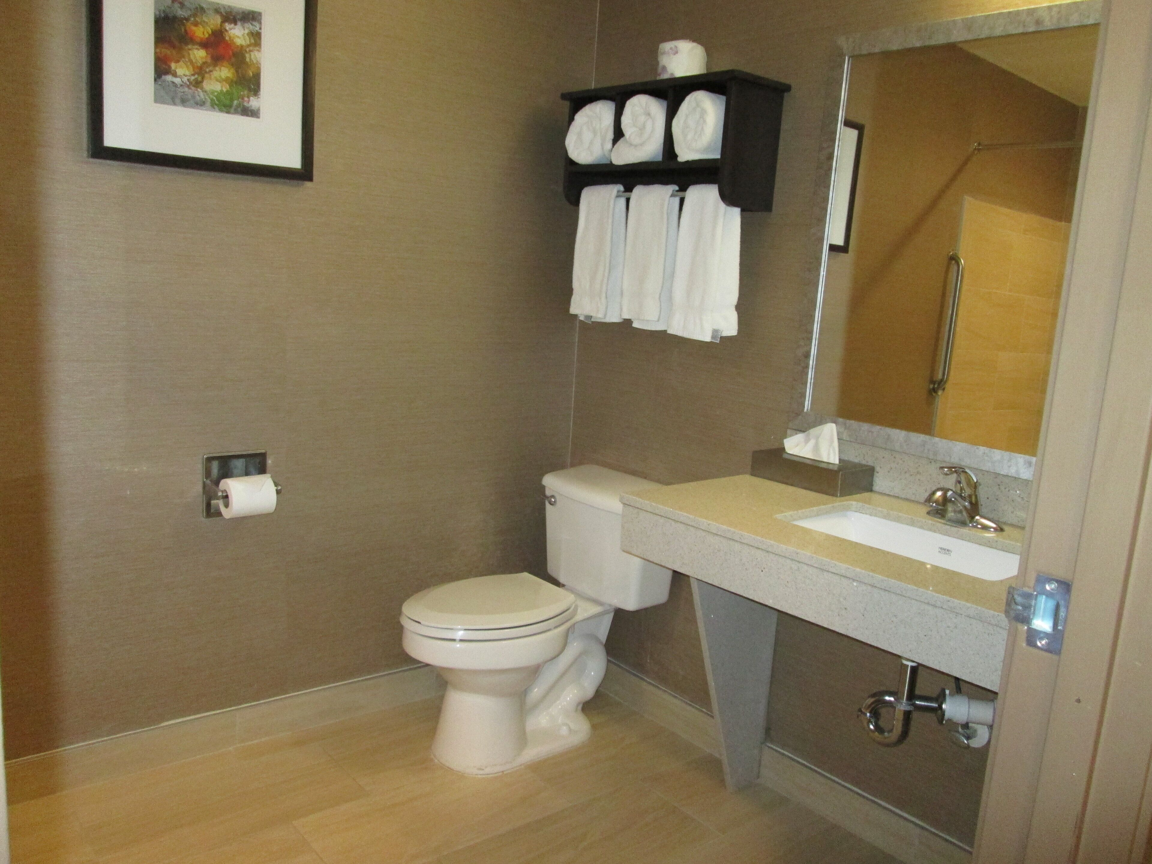 A bathroom with a toilet, sink, and a shelf with towels.