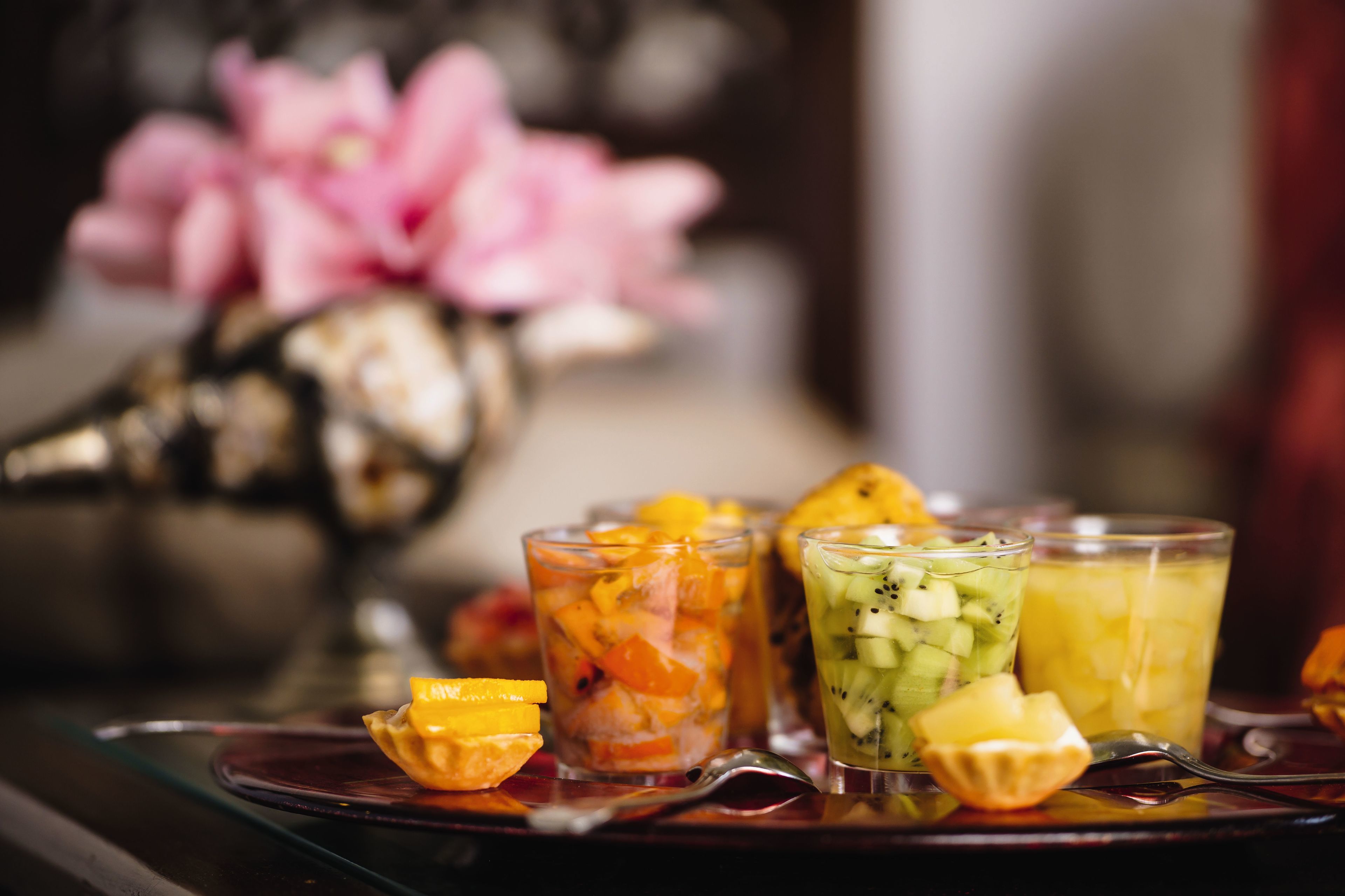 A tray with three fruit-infused drinks and a spoon.