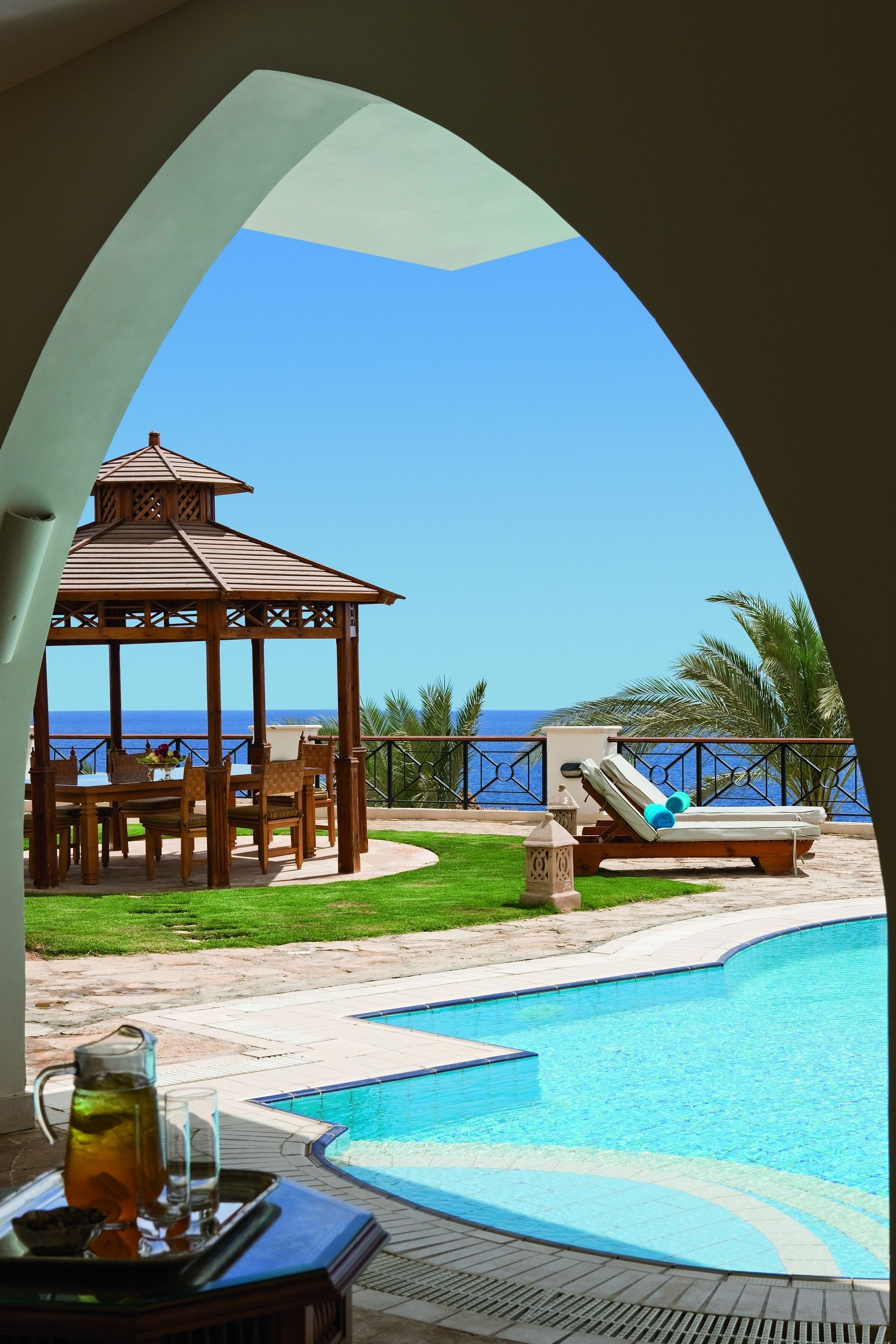 A poolside area with a gazebo, lounge chairs, and a view of the ocean.