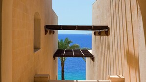 Un passadís arquejat amb vista al mar, una palmera i una pèrgola de fusta.