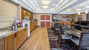 A hotel lobby with a buffet area, seating area, and a kitchen visible in the background. - La Quinta Inn & Suites by Wyndham Coeur d`Alene (Coeur d'Alene)