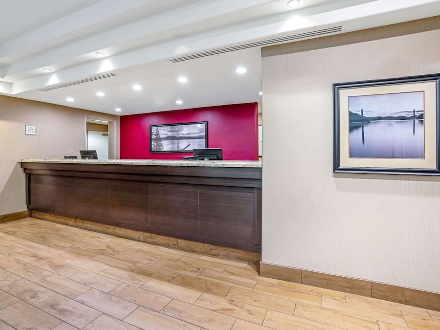A reception area with a red accent wall, a framed picture, and a wooden floor.