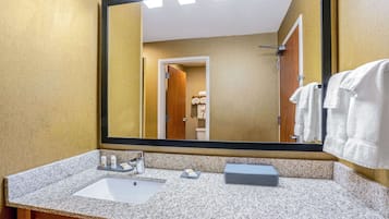 A bathroom with a granite countertop, a sink, a mirror, and a towel rack.