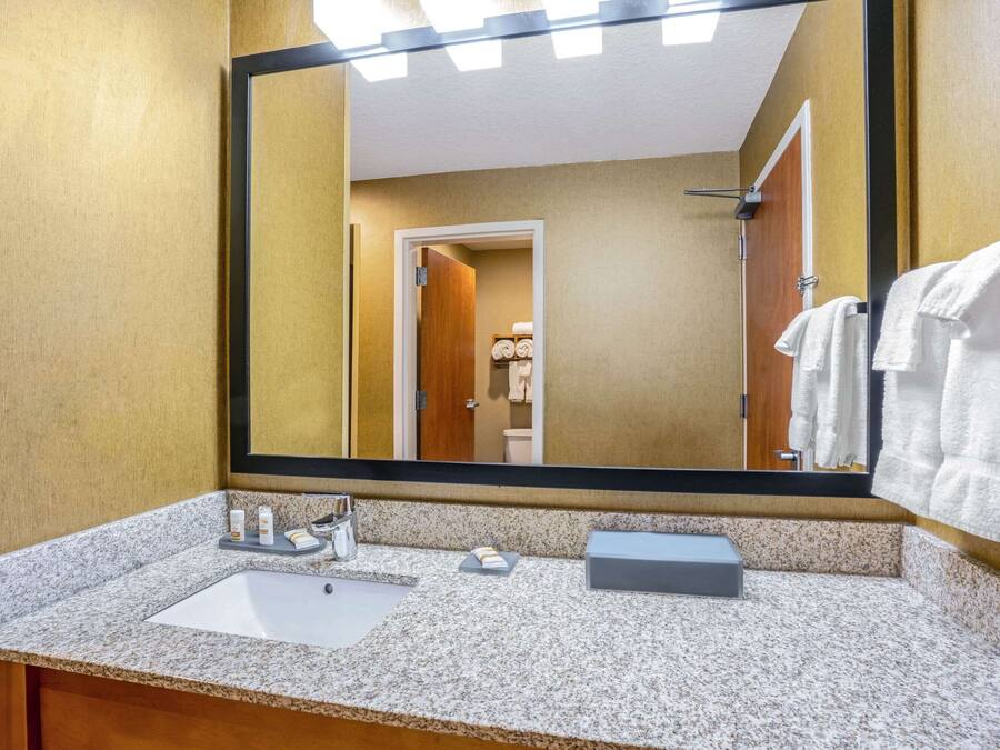 A bathroom with a granite countertop, a sink, a mirror, and a towel rack.