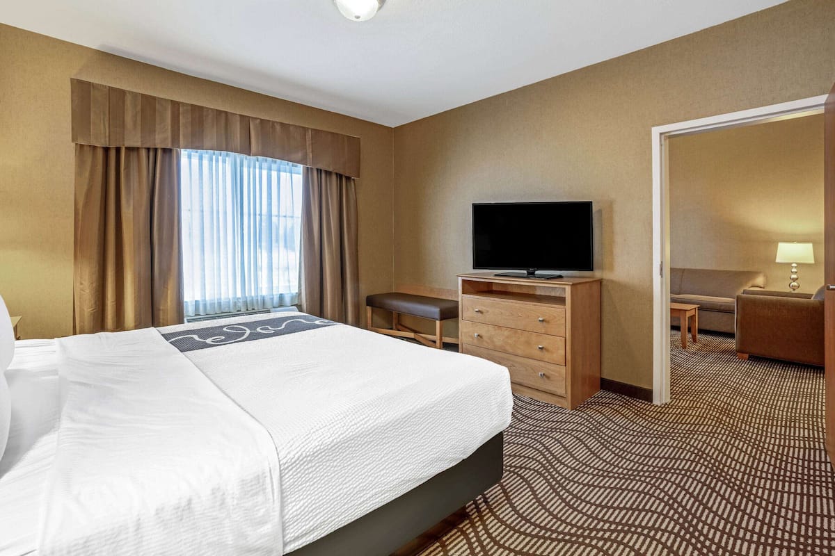 A hotel room with a large bed, a television, a desk, and a chair.