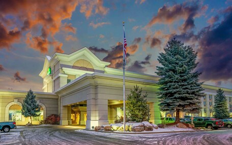 A hotel with a prominent American flag, a well-lit entrance, and snow-covered surroundings.