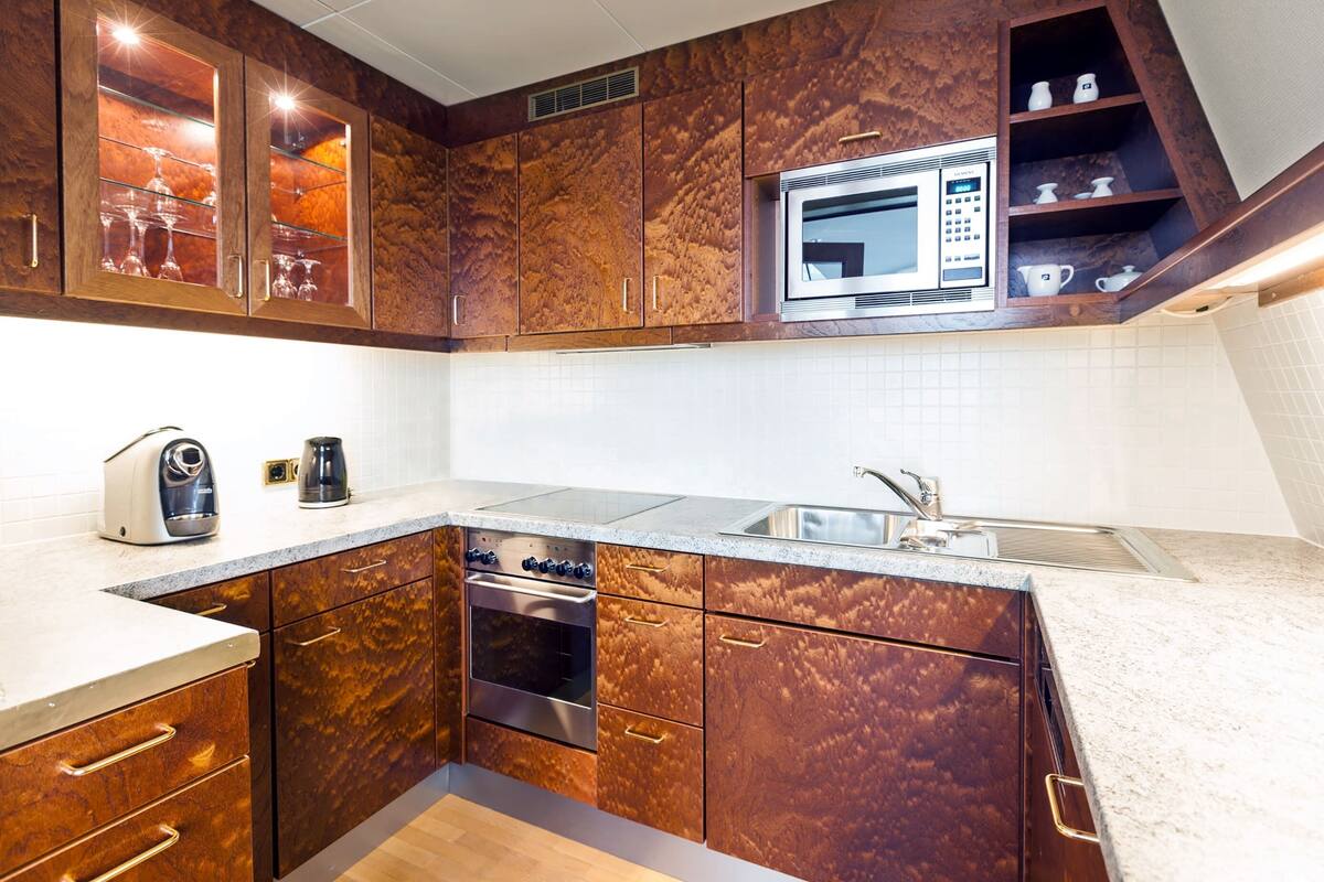 A modern kitchen with wooden cabinets, a microwave, and a coffee maker.