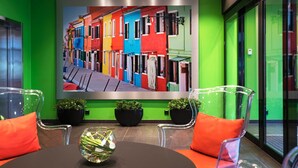 A modern interior with a vibrant green wall, a colorful street art mural, and a round table with chairs. - Thon Hotel Terminus (Oslo)