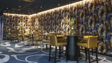 A room with a patterned wall, a round table, and bar stools.