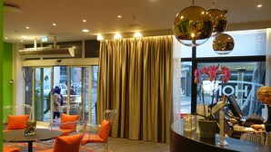 A hotel lobby with a round table, clear chairs, a large window, and a reception desk. - Thon Hotel Terminus (Oslo)
