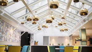 A modern interior with a high ceiling, glass panels, and multiple hanging spherical light fixtures. - Thon Hotel Terminus (Oslo)