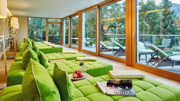 A modern interior with green upholstered seating, a magazine, and a balcony with outdoor furniture. - Relais & Châteaux Hotel Tennerhof (Kitzbuhel)