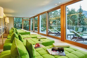 Ein modernes Interieur mit grünen Polstersitzmöbeln, einer Zeitschrift und einem Balkon mit Gartenmöbeln.