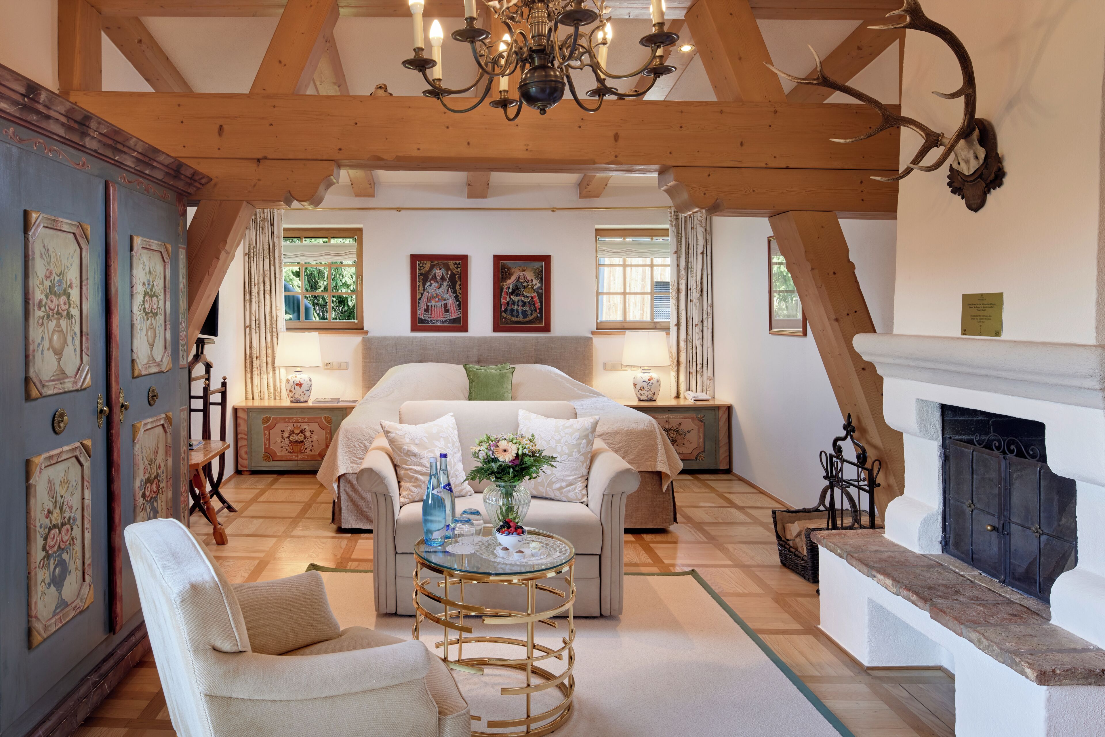 Um quarto amplo com teto alto, vigas de madeira, lareira e um espaço de estar aconchegante com sofá e poltronas.