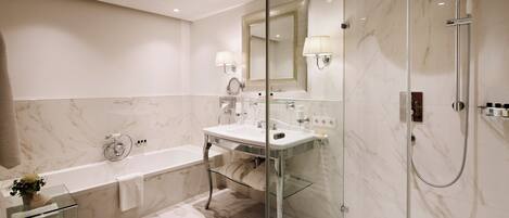Un baño moderno con ducha envuelta en vidrio, bañera independiente y tocador con espejo.