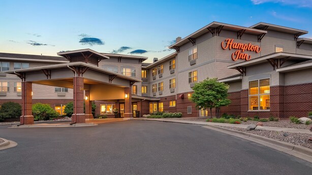Un hotel Hampton Inn con un diseño arquitectónico moderno, que presenta una entrada destacada y amplias ventanas.