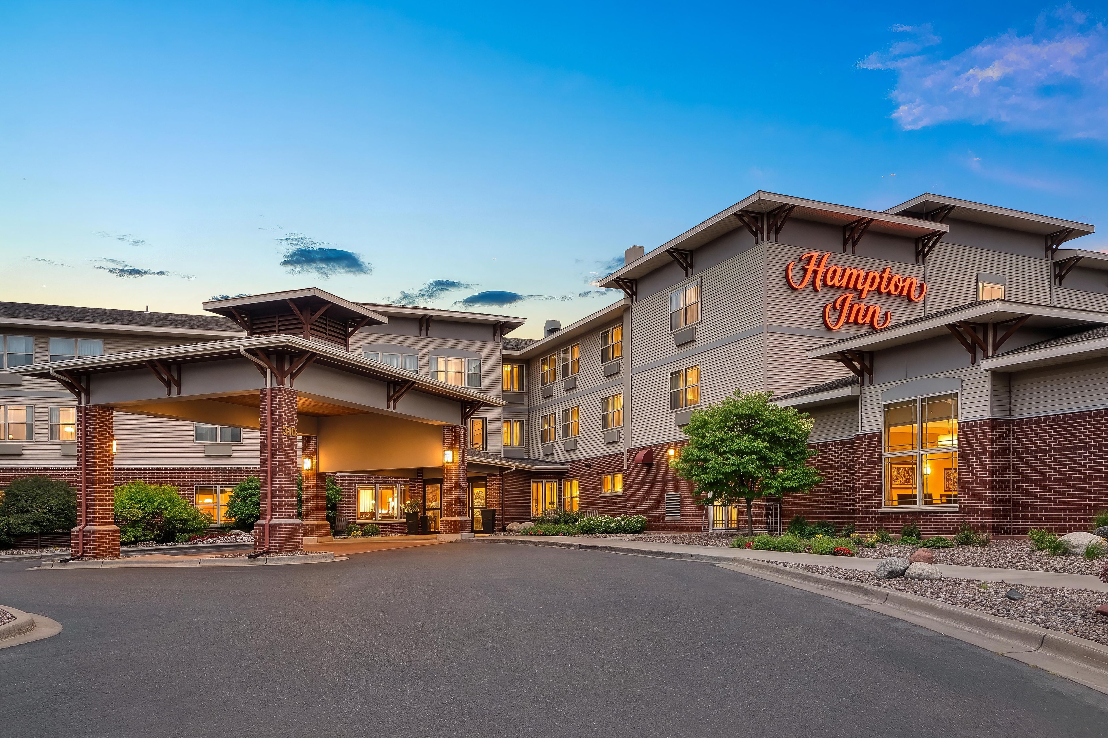 Een Hampton Inn hotel met een modern architectonisch ontwerp, met een opvallende ingang en meerdere ramen.