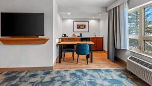 Una sala de estar moderna con televisor de pantalla plana, un comedor con mesa y sillas de madera, una cocina con armarios de madera y un ventanal con cortinas.